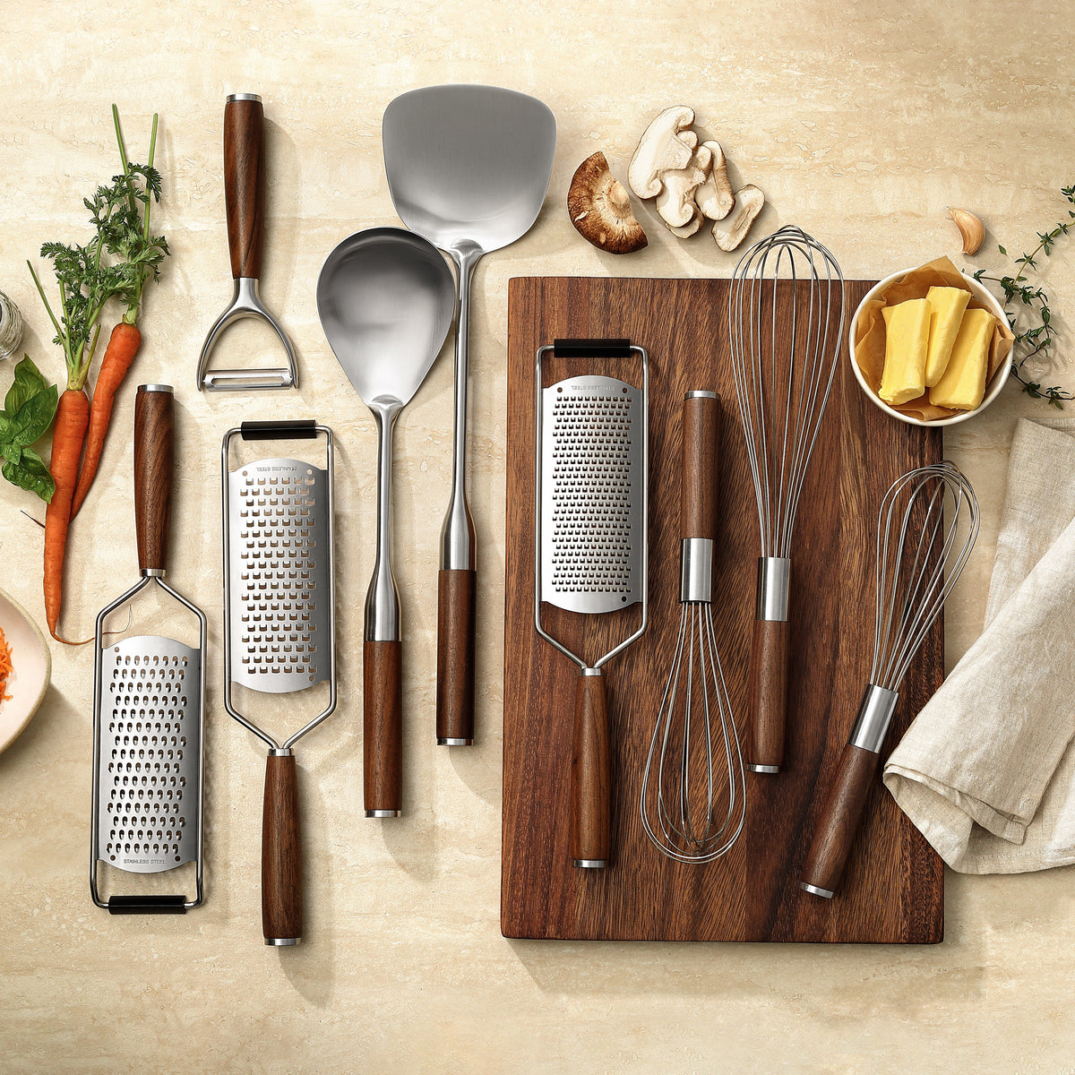 Die neun Küchenhelfer des Signature-Sets mit Griffen aus Walnuss auf einem Walnussbrett, von oben