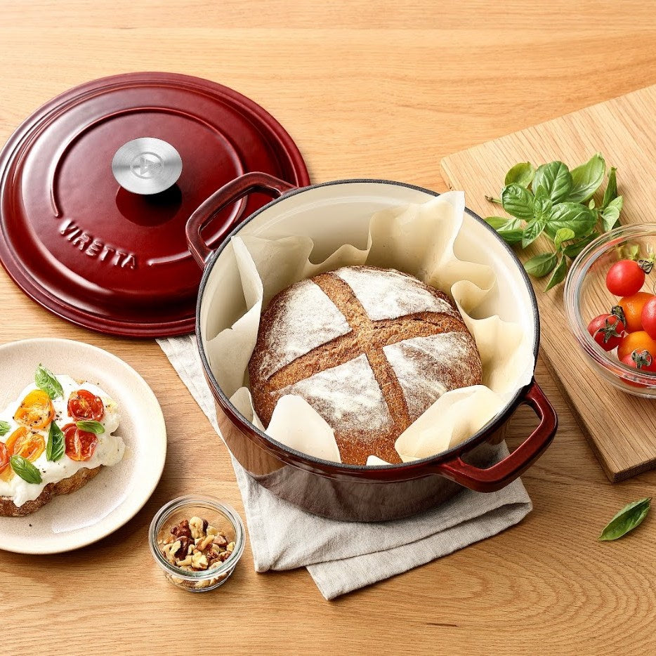 Johannisbeerroter Gusseisentopf mit selbstgebackenem Brot, daneben der Deckel #Farbe_Johannisbeerrot