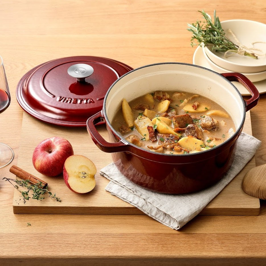 Johannisbeerroter Gusseisentopf mit Schweinefleisch und Äpfeln, daneben der Deckel #Farbe_Johannisbeerrot