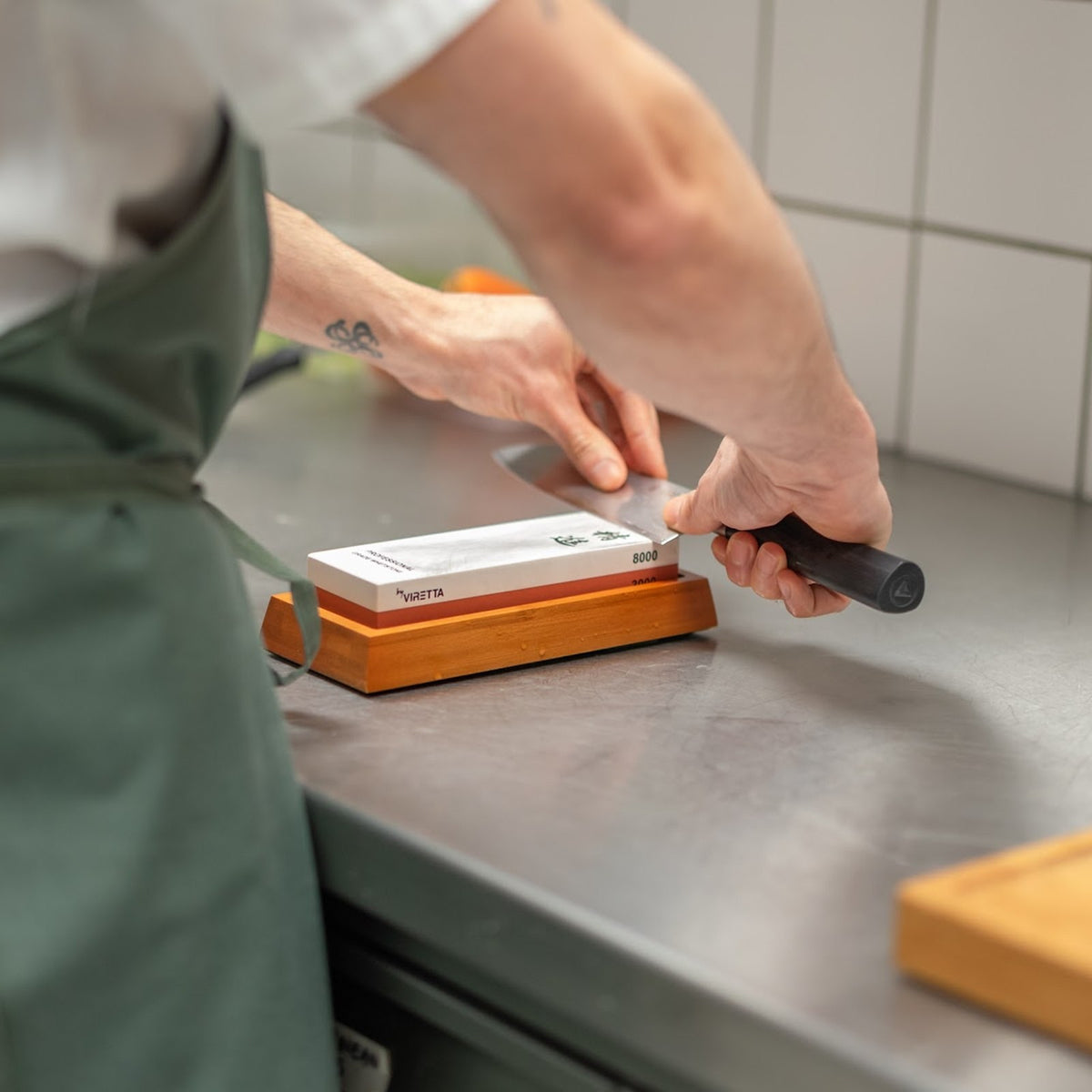 Ein Messer wird auf dem Shōjin Schleifstein 3000/8000 im Bambushalter in einer Restaurantküche geschliffen