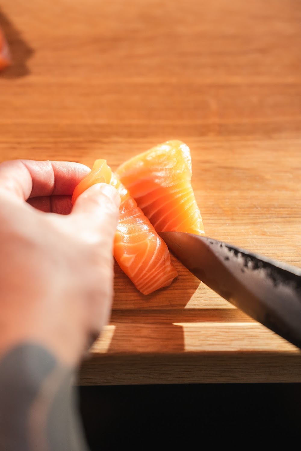 Lachs wird auf einem Holzbrett in Scheiben geschnitten