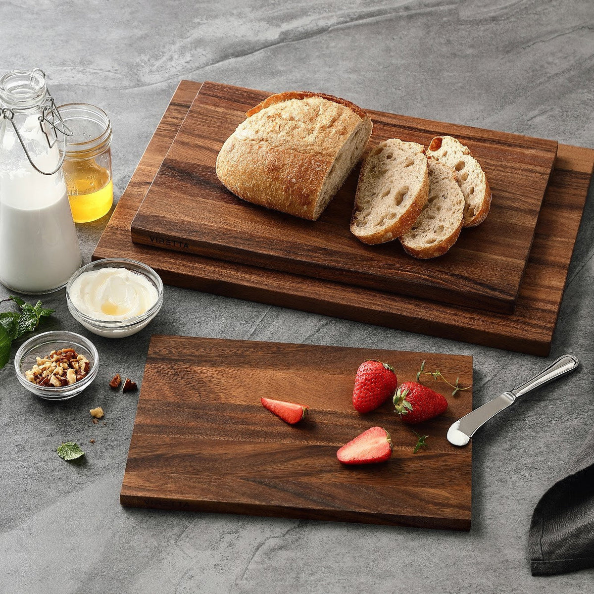 Schneidebretter aus Walnuss mit Sauerteigbrot und Erdbeeren