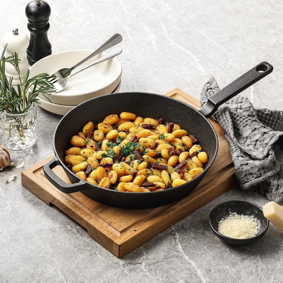 Gusseisenpfanne aus reinem Gusseisen mit gebratenen Gnocchi, auf einem Schneidebrett