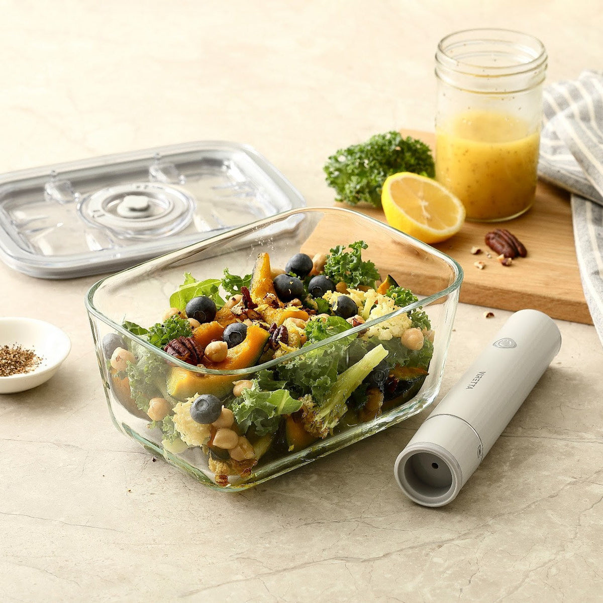 Vakuumbehälter aus Glas mit Salat – Deckel und elektrische Vakuumpumpe liegen daneben