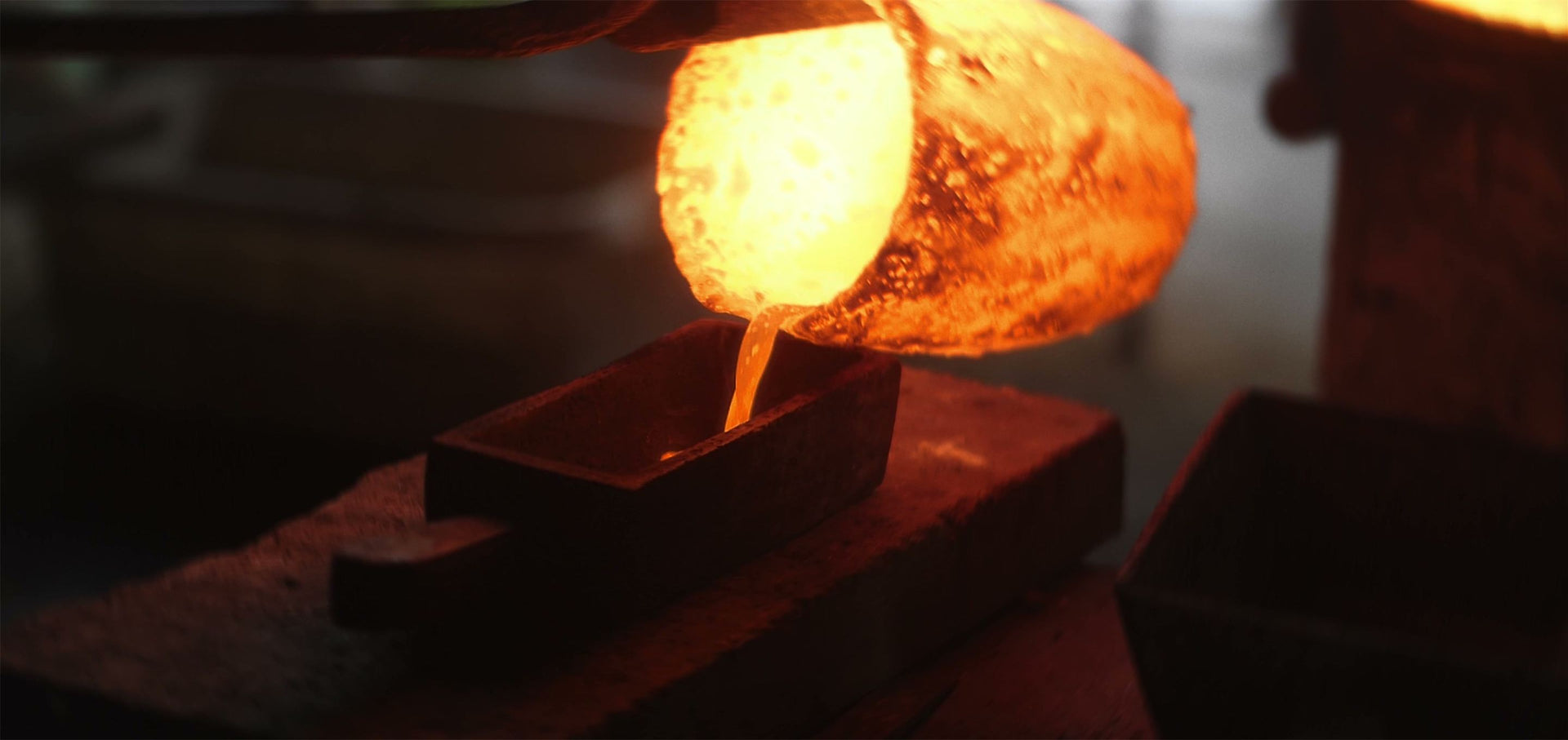 Glühendes, flüssiges Metall wird aus einem Tiegel in eine Gussform gegossen