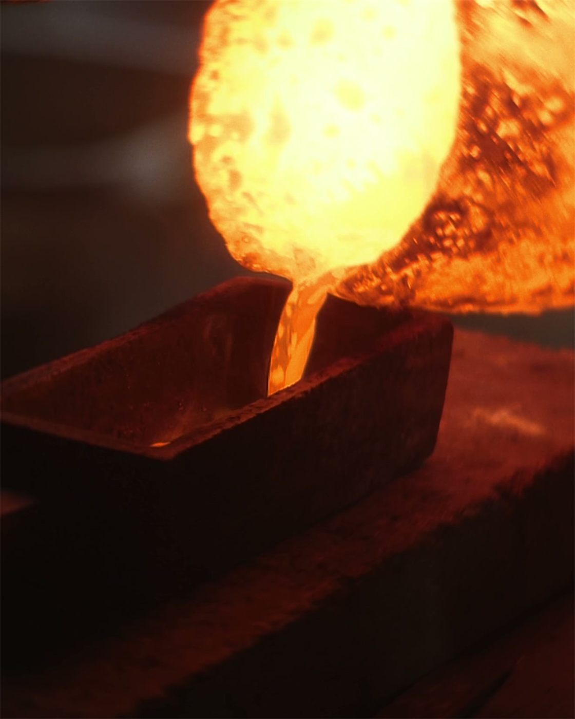 Glühendes, flüssiges Metall wird aus einem Tiegel in eine Gussform gegossen