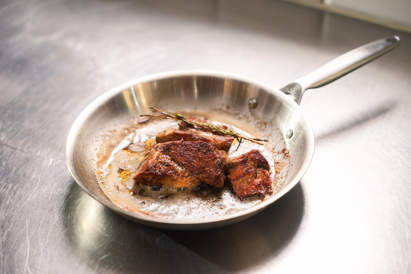 Ein Steak mit Rosmarin in einer Edelstahl-Bratpfanne bei Bryggerens Spisekammer